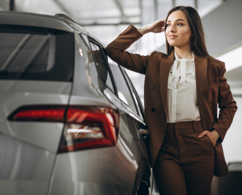 Young beautiful woman choosing car in a car showroom